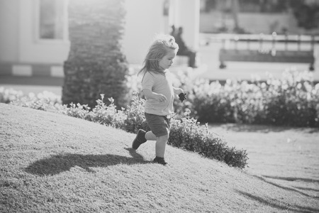 Happy kid having fun. Little adorable child running at meadowの写真素材