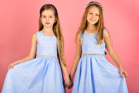 Happy children having fun indoors. Kids playing in summer dress. Little girls on pink backgroundの写真素材