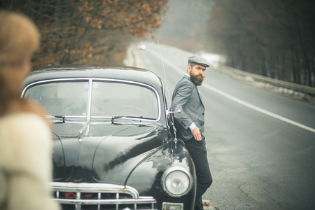 nostalgia concept. nostalgia and retro car at bearded man and woman in coatの写真素材