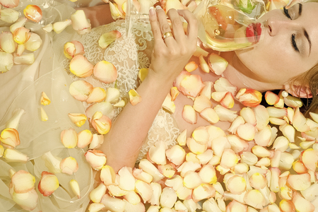 Fashion model woman fece close up. Face woman wiht happy emotion. Blonde woman in bath with yellow petalsの写真素材