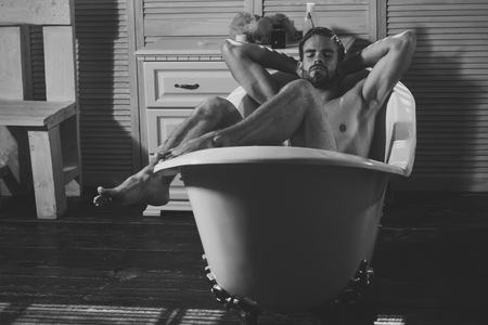 Sexy macho relax naked in bathtub in bathroomの写真素材