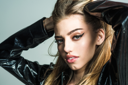 Makeup look for woman with soft skin. Sexy woman with stylish long hair in black leather coat. Trendy girl with makeup on sensual face. Beauty and hairdresser. Fashion cosmetics for skincare.の写真素材