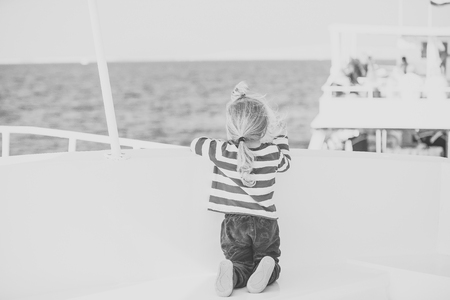Child Childhood Children Happiness Concept. Small cute child sitting back on white yacht.の写真素材