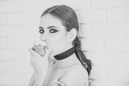 Woman face beauty. Woman eat apple on white brick wallの写真素材