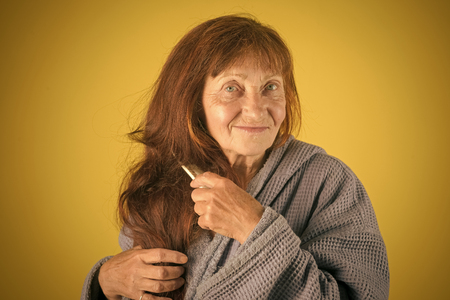 Senior woman in pension and retirement. Haircare and beauty. Hairdresser and barbershop. Woman comb long red hair.の写真素材