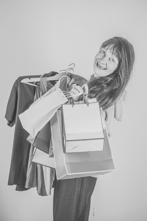 Woman with long red hair hold colorful shopping bag. Clothes in hand of happy woman.の写真素材