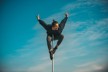 young man practicing on the pole on blue sky background.の写真素材