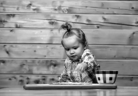 Kid play. cute child cooking with dough, flour and bowl on woodの写真素材