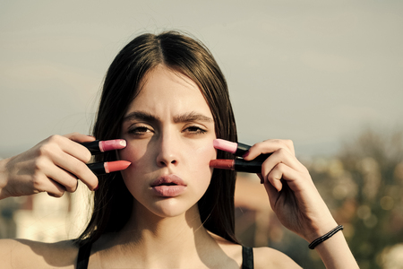 Face girl for magazine cover. Girl face portrait in your advertisnent. Model posing with pink lips and lipsticks on blue skyの写真素材