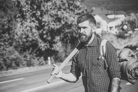Brave man. Brutal man. Man hiker with beard hold axe and backpack on roadの写真素材