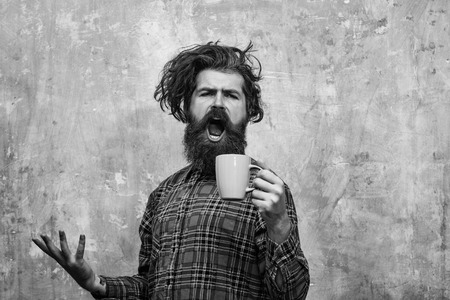 Morning coffe. singing bearded man pulling stylish fringe hair with blue cupの写真素材