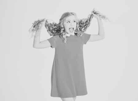 Haircare. Little girl with curly long hair and makeup. Beauty, kid fashion, cosmetics, healthy hair. Hair salon, barber, skincare, look. Hairdresser, makeup, shampoo. Happy girl in red dress isolated on white.の写真素材