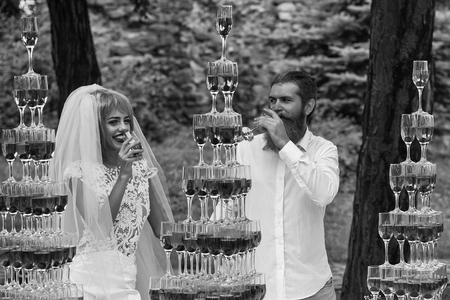 Wedding of stylish couple. wedding couple with pyramids of wine glasses outdoorの写真素材