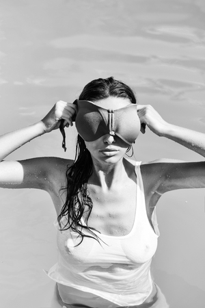 sexy pretty brunette in the pool with wet shirt. brunette holding pink swimsuit braの写真素材
