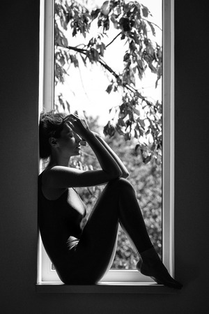 depression apathy loneliness. lack of vitamins. pretty sexy sporty woman on windowの写真素材