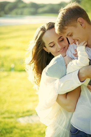the happiness of parenting. Man, woman smile to child on sunny dayの写真素材