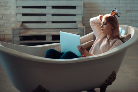 Woman work on computer in home bath. Buy online and digital marketing. Businesswoman has modern life with new technology. Agile business and communication. Girl relax in bathtub with laptop keep blogの写真素材