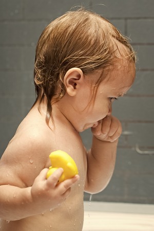 boy takes bath procedures. Child with duckling in showerの写真素材