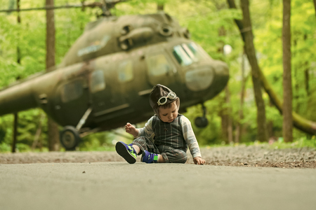 young pilot. The concept of the choice of profession. Baby boy in pilot helmet with glasses on asphalt roadの写真素材