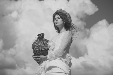 Summer vacation, holidays and celebration. Winery tour concept. Girl with wicker wine bottle on cloudy skyの写真素材