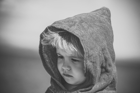 sad child in a hood. small boy or kid in blue terry hood sunny summerの写真素材