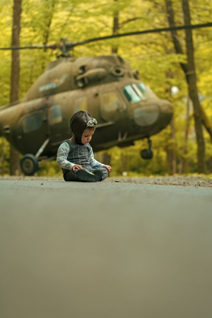 future pilot. Kid sitting at helicopter on natural backgroundの写真素材