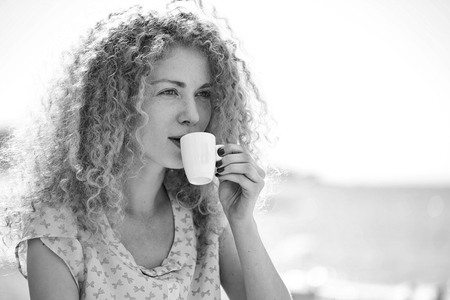 woman is drinking fragrant coffee. Woman drinking coffee outdoorの写真素材