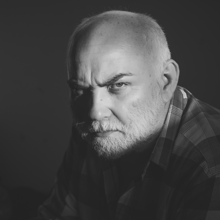 older man with a serious look. Man with grey beard, frown brows on serious faceの写真素材