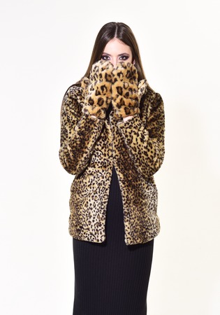 Winter fashion and beauty. Woman in leopard fur coat isolated on white. Look of fashion model with...