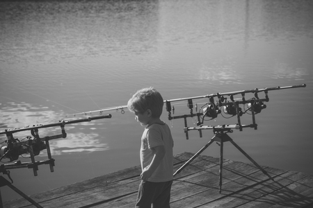 rest on a fishing trip. Little boy with fishing rods on pierの写真素材