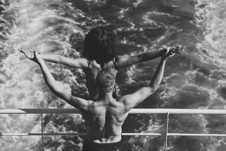 Couple in love . Attractive couple feel free and enjoy summer vacation. Freedom concept. Nude couple stands on deck of cruise liner with sea waves on background, rear view. Couple in love travellingの写真素材