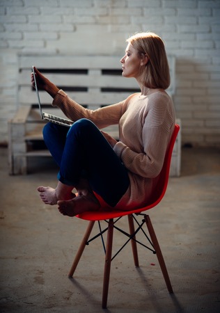 Businesswoman has modern life with new technology. Girl with laptop keep blog sitting on chair. Agile business and communication. Buy online and digital marketing. Woman work on computer at home.の写真素材