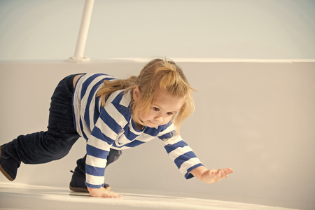 child by the sea in a boat. Little boy child playing on white yacht.の写真素材