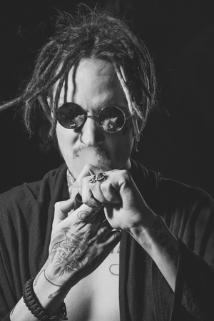 smoking marijuana. Drug addiction. Hippy smoker with dreadlocks in sunglasses and bare chestの写真素材