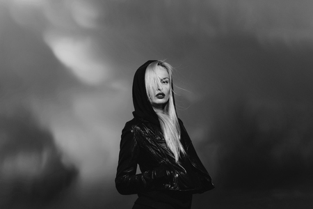 fashion portrait of a woman in the background of a storm. model, pretty blonde woman with red lips in leather jacketの写真素材