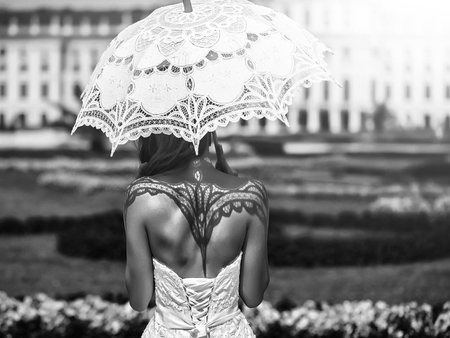 Girl with a lace umbrella. pretty wedding woman, sexy bride with white umbrella sunny outdoorの写真素材