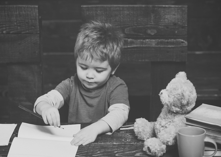 alternative education. Small kid writing in textbook. Diligent boy learning letters. Early learning conceptの写真素材