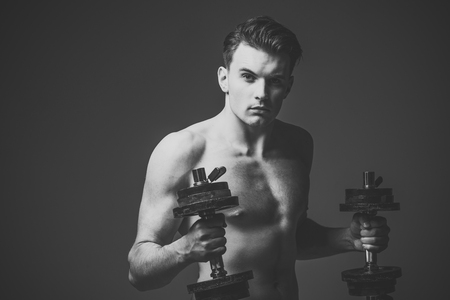 Work out concept. Man with torso, muscular macho with six packs, holds dumbbells, dark backgroundの写真素材