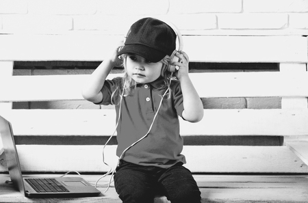 child is a music lover. little kid wearing headphone near laptop on white backgroundの写真素材