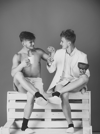 Housework and fashion concept. Men smiling on wooden bench on blue backgroundの写真素材