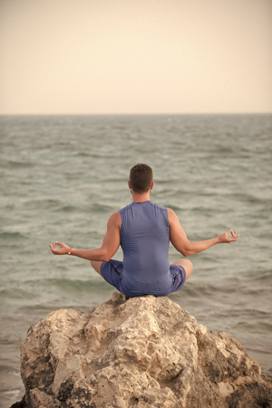 concept of harmony. boy practicing yoga near blue oceanの写真素材
