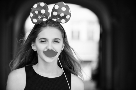 Decorative props on stick. Holiday, birthday, anniversary celebration. Happy pretty girl with cute mouse ears and red lipsの写真素材