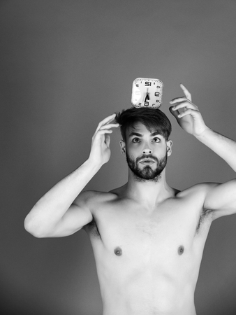 Time, timing. Sexy man holding alarm clock on headの写真素材