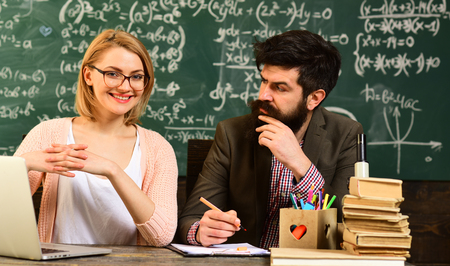 Smiling adult students during break in classroom interior, Student studying online courses with computer, Private tutors often have vast teaching experience, Old books on a round wooden tableの写真素材