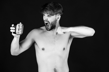 inexorable time. handsome muscular angry shouting man with alarm clockの写真素材