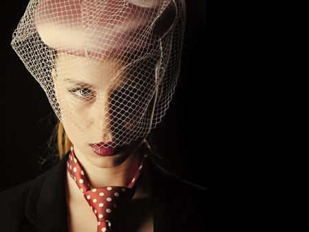 Beauty Fashion model girl. Fashion look. Girl in tie with red dots on neck. Retro or vintage style concept. Lady posing on black background. Fashion and accessories.の写真素材