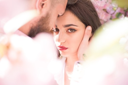 He is absolutely mine. Sensual woman enjoy intimacy with man. Couple in love hug among blossoming trees. Skincare and freshness. Desire and romance. Spring is season for love.の写真素材