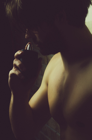 Male cologne. macho with naked chest smelling perfume scentの写真素材