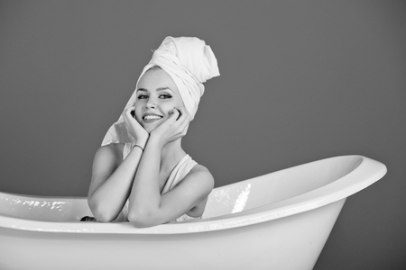 women's leisure. happy girl. pretty sexy woman with towel turban on head sitting in white bathtub on blue background, spa and beauty, relax and hygiene, healthcare and housekeep, copy spaceの写真素材