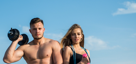 Fitness. Fitness training on blue sky. Fit man and woman with fitness tools outdoor. Fitness trainers with dumbbells. Commit to be fit, copy space.の写真素材
